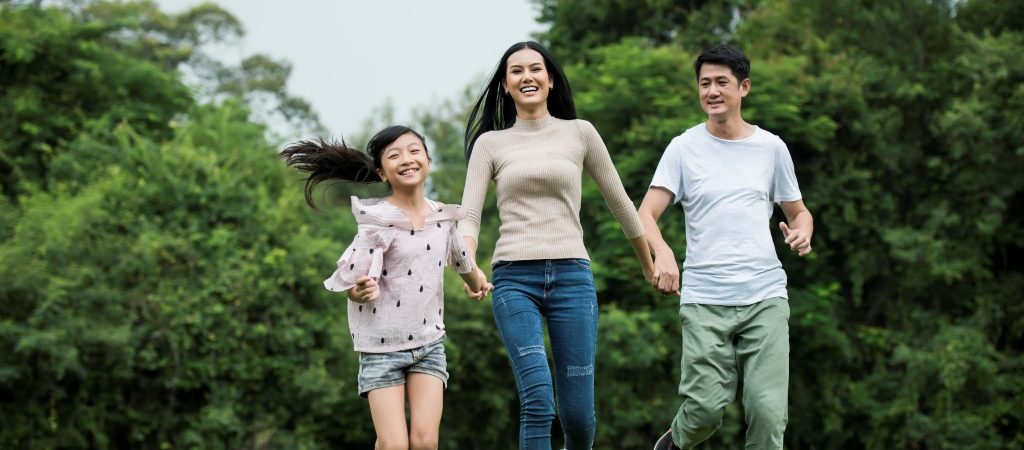 Happy family is having fun Mother, father and daughter are running in park.