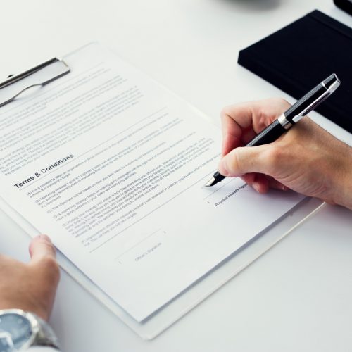 Closeup of hand signing paper workspace